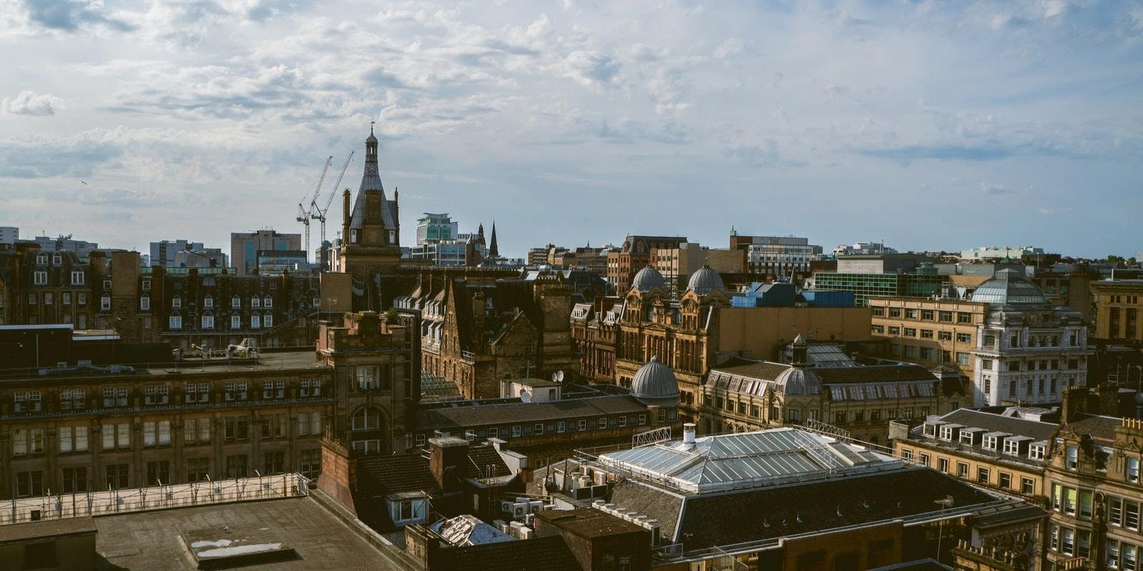 Rooftops in Glasgow under a partly cloudy sky